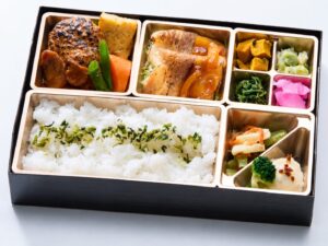 デミグラスソースのハンバーグと生姜焼き、副菜を盛り付けた弁当