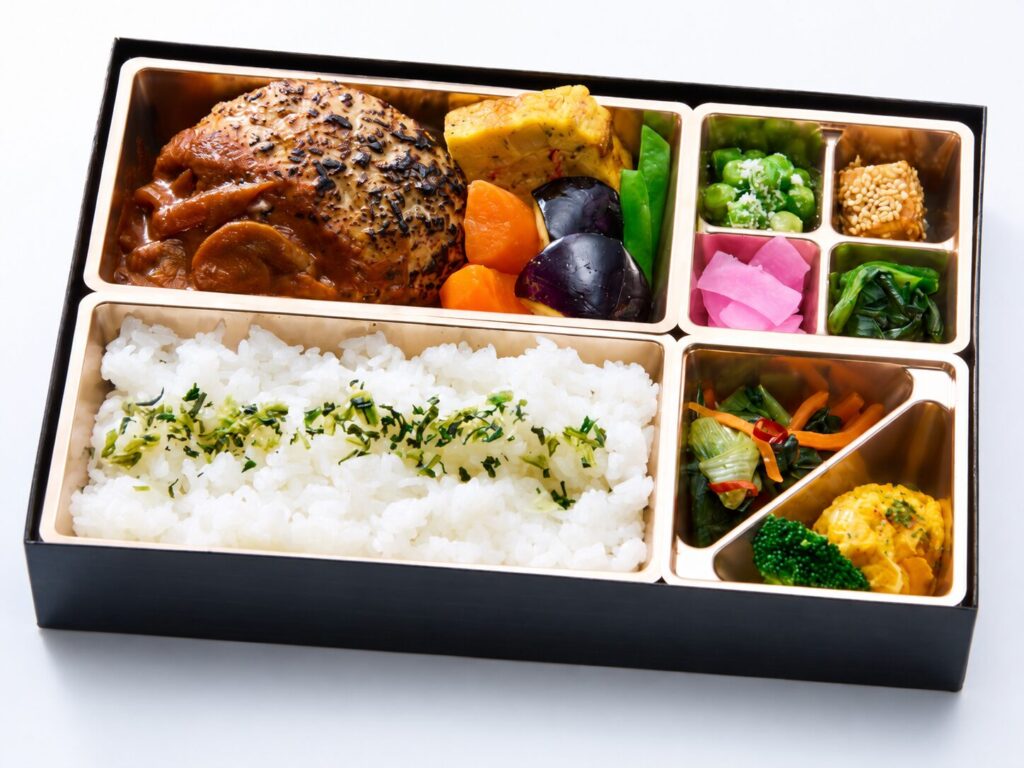 デミグラスソースのハンバーグと彩り豊かな副菜を盛り付けた弁当