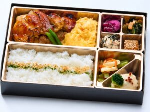 照り焼きソースのチキンステーキとスクランブルエッグ、副菜を盛り付けた弁当