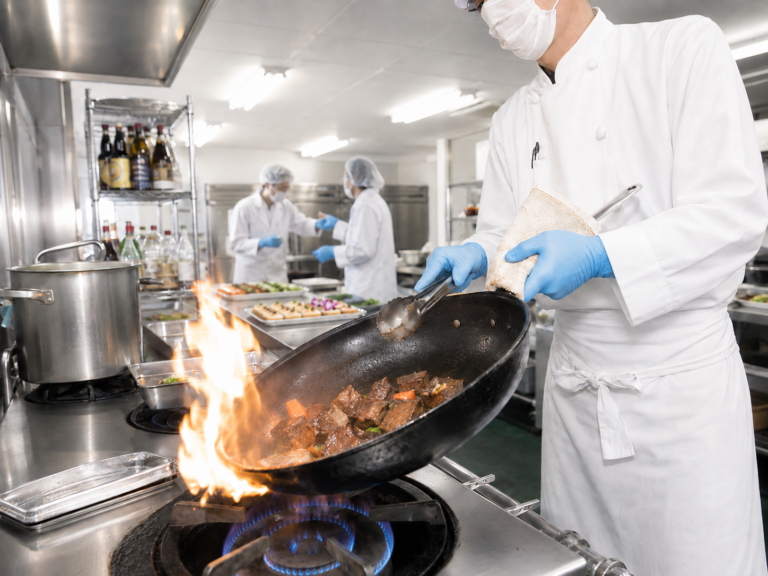 アポルテフードファクトリーの調理場で衛生管理のもと肉料理を加熱調理するスタッフ